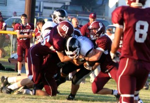 Jaden Vetick, Chevy Henneman, and Dakota Riecken gang-tackle a Spalding/Spalding Academy runner as Taylor Fuston and the Cougar bench watch. Photo Credit/Steven Hosch.