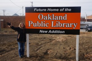 Rosa Schmidt, Oakland Library Director. next to the sign placed on the ground of the future library expansion site. Photo Credit/Denise Gilliland, Editor and Chief, Kat Country Hub.
