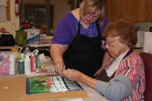 Connie Buskohl-Barney assists Marcella Hennig with her painting stroke as part of the Mneme Therapy demonstration at Oakland Heights last week.  Photo Courtesy of Mary Loftis.