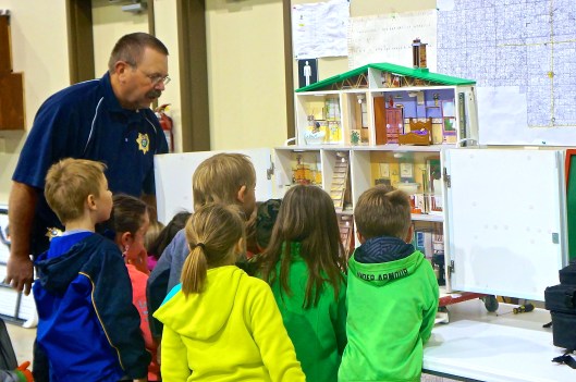 A house displays the many things people should not be doing that can cause fires. Jeff Going, Lyons fire department member and a state fire marshall, quizzes this group of kindergartners on what people should not do. Photo Credit/Denise Gilliland, Editor and Chief, Kat Country Hub. 