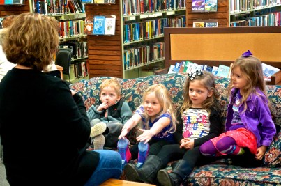 Blaise Hartwell, from left, Avery Christensen, Hilary Ray and Laityn Johnson enjoy stories read by Oakland Library Director Rosa Schmidt. Photos credit of Denise Gilliland, Editor and Chief, Kat Country Hub.