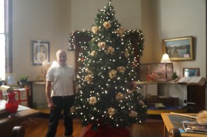 Tom Wallerstedt just decorating the Christmas Tree at the Swedish Heritage Center with his handmade corn husk rose ornaments. Photo Credit/Denise Gilliland, Editor and Chief, Kat Country Hub.