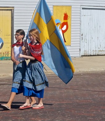 Mia Linder, left, and Ellen Magnusson carry the Swedish flag through the parade at the Oakland Swedish Festival. Photo Credit/Denise Gilliland, Editor and Chief, Kat Country Hub. 