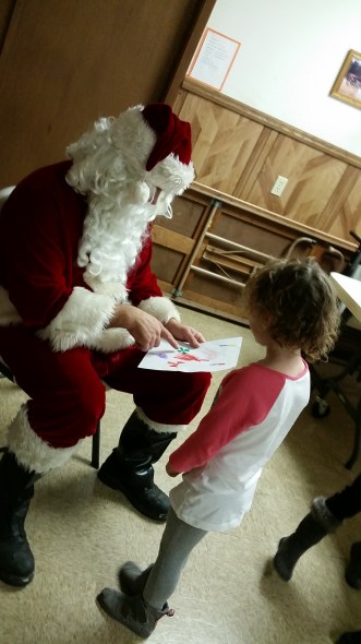 Josie Peterson shows her art work to Santa while he visited the youngsters in Oakland at the Vets Building.